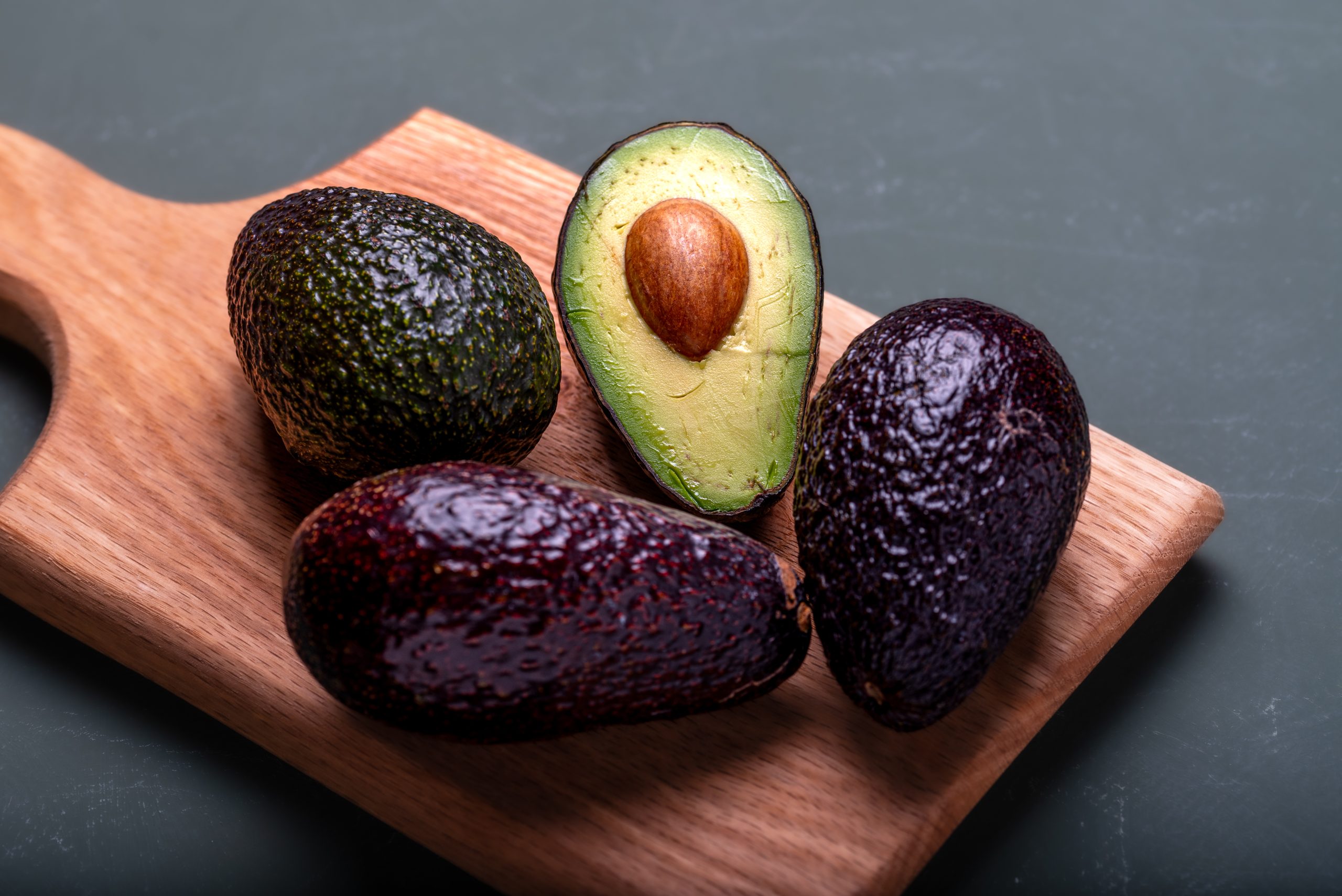 Fresh avocados on a brown wooden board