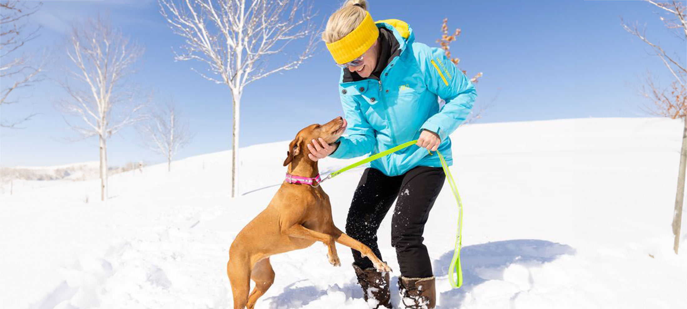 Woman and dog playing in the snow